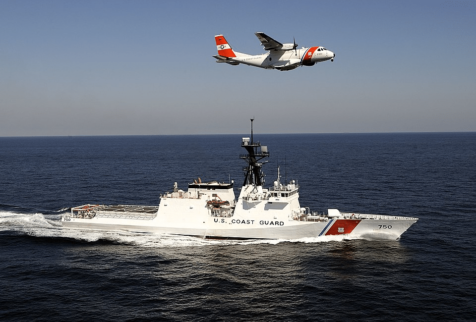 U.S. Coast Guard cutter and surveillance aircraft patrol open waters—symbolizing defense readiness amid growing maritime cybersecurity threats.