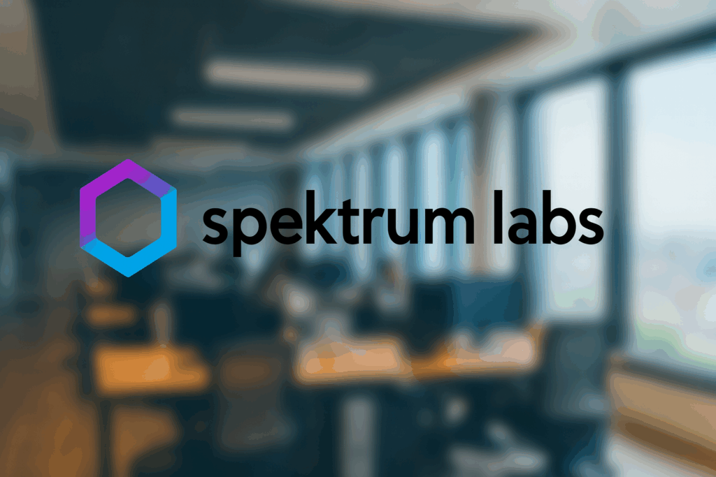 Spektrum Labs logo displayed over a blurred modern office background, representing AI-powered cyber resilience and enterprise cyber insurance solutions.