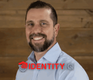 Michael Scheumack, Chief Innovation Officer at IdentityIQ, smiling in a professional headshot with the IdentityIQ logo overlay, representing identity theft protection and fraud prevention services.